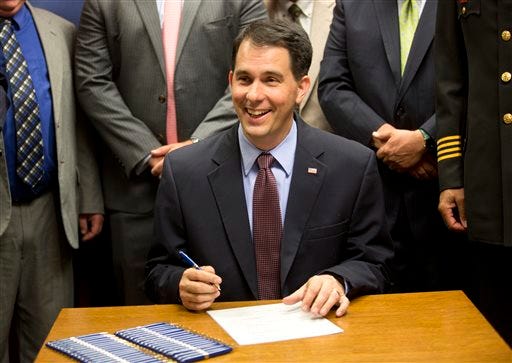 Wisconsin Gov. Scott Walker signs a gun bill at the Milwaukee County Sheriff's office that eliminates a 48-hour waiting period for handgun purchases. Wednesday, June. 24, 2015, in Milwaukee.  (AP Photo/Jeffrey Phelps