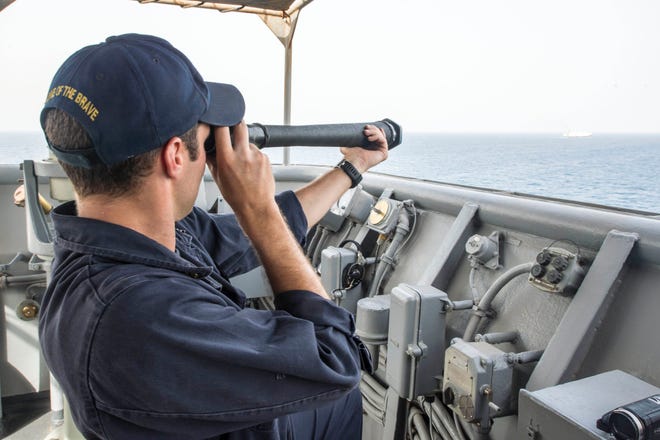Quartermaster 2nd Class Andrew Wilson, from Chatanooga, Tenn., monitors a passing chip with a spy glass during a strait transit detail aboard the dock landing ship USS Fort McHenry (LSD 43).