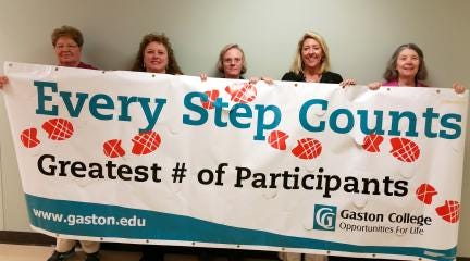Pictured, from left, Gaston College employees Donna Blake, Tonya Propst, Rebecca McLain, Helene Burnham and Dr. Karen Less hold up a banner. The Economic and Workforce Development Division team had 20 participants to compete in the competition to promote health and wellness.