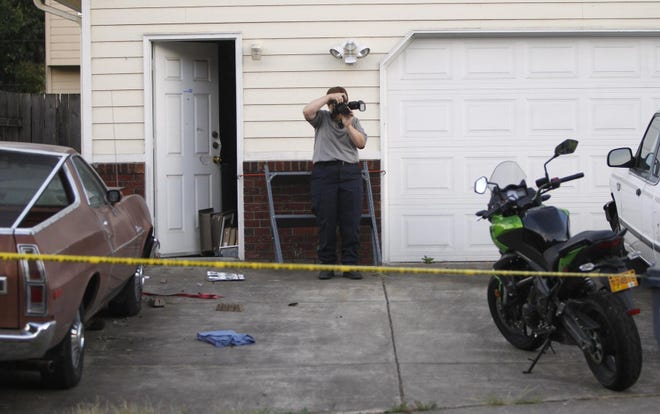 An Oregon State Police Forensics investigator photographs vehicles in the driveway of a residence police cordoned off in Springfield, Ore., where they are investigating after a welfare check on a woman June 23, 2015. (Andy Nelson/The Register-Guard)