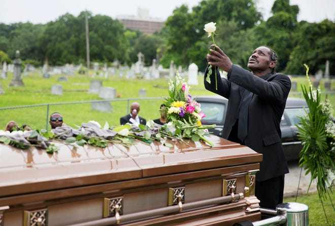 Gary Washington holds up a rose before placing it on the casket of his mother, Ethel Lance, following her burial service on Thursday in Charleston. Lance was one of the nine people killed in the shooting at Emanuel AME Church on June 17.