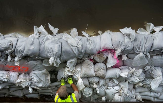 A worker stacks sandbags to reinforce the wall against the rising Illinois River on the Peoria riverfront Thursday morning.