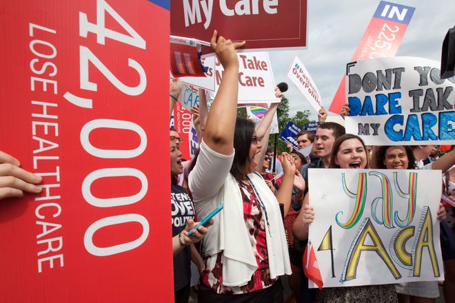 Jessica Ellis, right, holds a sign that says "yay 4 ACA," as she and other supporters of the Affordable Care Act cheer as the opinion for health care law is reported outside of the Supreme Court in Washington on Thursday.