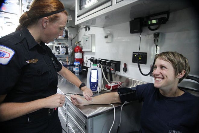 Parametic Kelly Fisher demonstrates how she checks a pateints pulse, Bentley Andrews who is a firefighter for Asheville Fire Department on the Ambulance Bus from Bumcob county Thursday morning at Cleveland County Fairgrounds.