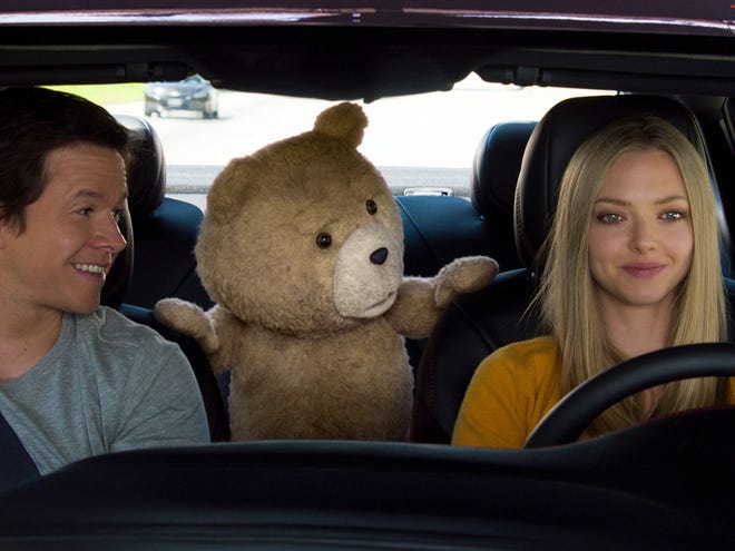 In this image released by Universal Pictures, Mark Wahlberg , from left, the character Ted, voiced by Seth MacFarlane, and Amanda Seyfried appear in a scene from "Ted 2."