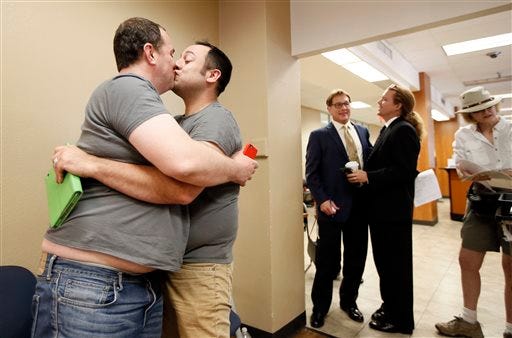 Kenneth Denson, left, and Gabriel Mendez kiss after hearing the U.S. Supreme Court news allowing same sex marriage Friday, June 26, 2015, in Dallas, at the county clerks office. (AP Photo/Tony Gutierrez)