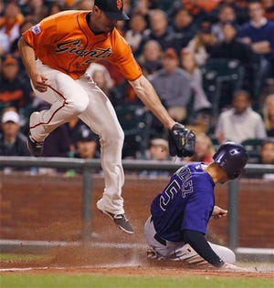 Colorado Rockies' Carlos Gonzalez (5) slides safely under the tag by San Francisco Giants pitcher Mike Broadway during the ninth inning of a baseball game, Friday, June 26, 2015, in San Francisco. Gonzalez scored on a wild pitch. (AP Photo/George Nikitin)