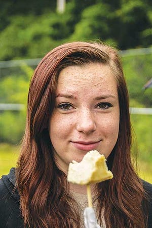 Photo by Warren Westura/New Jersey Herald - Nicole Schuman, 15, of Hopatcong, enjoys some cheese cake on a stick at Saturday’s Just Jersey Food Truck and Music Festival at Waterloo Village in Byram.