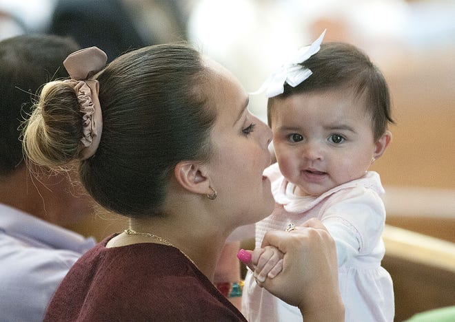Lily Montoya watches sister Sofie, 6 months, while their mother Rosa Medina De Montoya reads during the Spanish Mass at Queen of the Universe in Middletown 1:00 p.m. on Sunday, June 21, 2015.