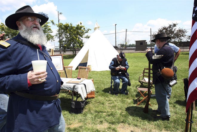 Lauren Kastner/The Hawk Eye Left, Al Ourth, Charlie Varboncoeur and Tom Swearingen gather at a re-enactment of an 1865 Civil War headquarters camp Saturday at the Burlington Depot. Right, Ralph Logan and Ourth pack gunpowder into a cannon during the demonstration. The re-enactment was part of a fundraising effort to renovate the historic depot.