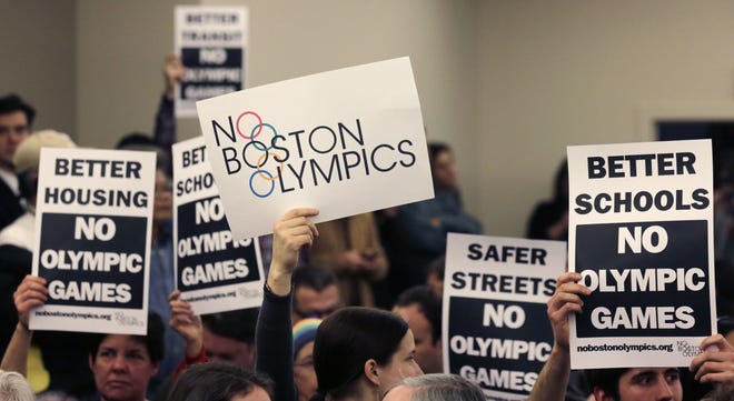 People in the audience hold up placards against the Olympic Games coming to Boston, during the first public forum regarding the city's 2024 Olympic bid, in Boston on Feb. 5. AP Photo/Charles Krupa, File