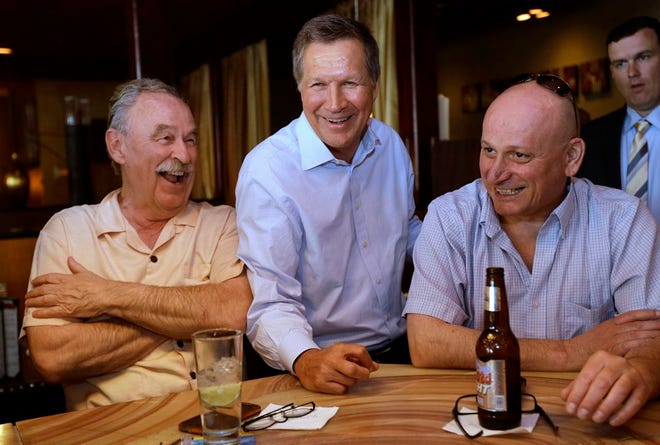 In this May 6, 2015, file photo, Republican Ohio Gov. John Kasich, center, greets patrons at a bar in a restaurant in Nashua, N.H. Kasich will formally announce his plans for the 2016 presidential race on July 21. The two-term governor, who leads one of the nation’s premier swing states, is expected to formally join the crowded Republican primary field at an announcement set for Ohio State University, according to senior advisers. The advisers spoke on the condition of anonymity so as not to pre-empt the announcement. (AP Photo/Steven Senne, File)