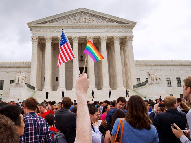 In this Friday June 26, 2015, file photo, a man holds a U.S. and a rainbow flag outside the Supreme Court in Washington after the court legalized gay marriage nationwide.