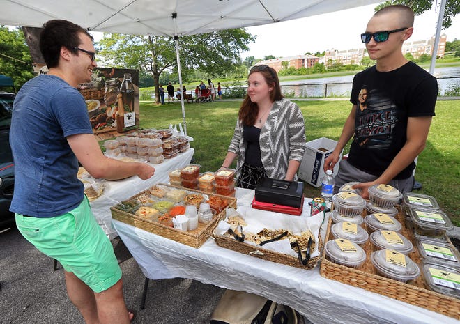 Tierney Standring and Colin McCarthy of Karimah's Kitchen tend to Mathias Hasler of Zurich, Switzerland, as he tries different Lebanese dips at the Exeter Farmers' Market on Thursday.

Ioanna Raptis/Seacoastonline