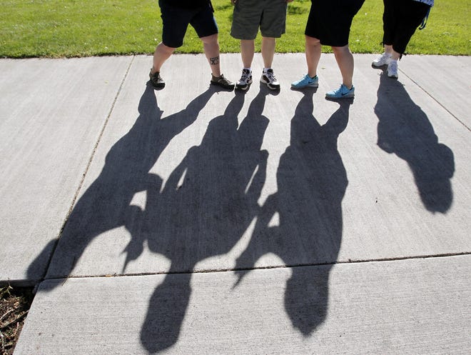 Before starting a walk at Alton Baker Park, members of Jill Rainer's walking group snap photos of their long, thin shadows -- a source of encouragment that they will shed pounds. (Paul Carter/The Register-Guard)