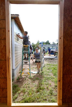 DARON.DEAN@STAUGUSTINE.COM Timmie Gray nails on siding as Crystal Gray brings another ladder while the two work with volunteers from Sunshine Rotary on a Habitat For Humanity house on Gray Jay Drive on Saturday morning, June 27, 2015.