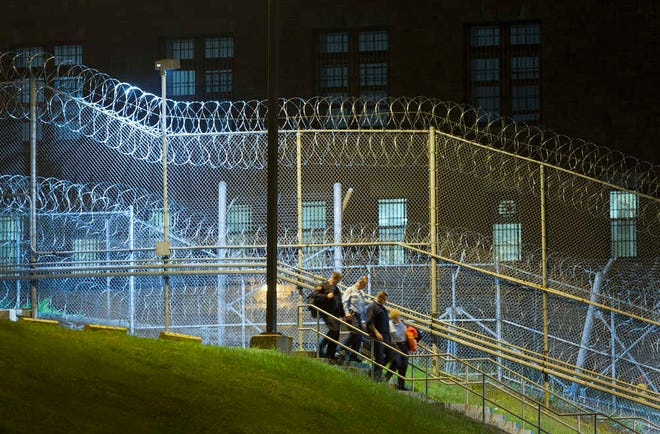 FILE - In this June 15, 2015, file photo, corrections officers walk next to a fence covered in razor wire as they leave work at Clinton Correctional Facility in Dannemora, N.Y. The June 6 escape by David Sweat and Richard Matt spotlighted apparent security lapses in a prison where a complex escape plan may have been rehearsed for weeks and the breakout went undetected for as long as six hours. But it also bared a culture of surprising liberties and personal relationships in a maximum-security prison where two convicted murderers--one with a history of escaping--were in privileged "honor" housing. A guard acknowledged giving one of them tools and access to an off-limits area in exchange for not only prison intel, but also paintings. And an instructor stands accused of helping the two escape after hatching a plot to kill her husband. (AP Photo/Mark Lennihan, File)