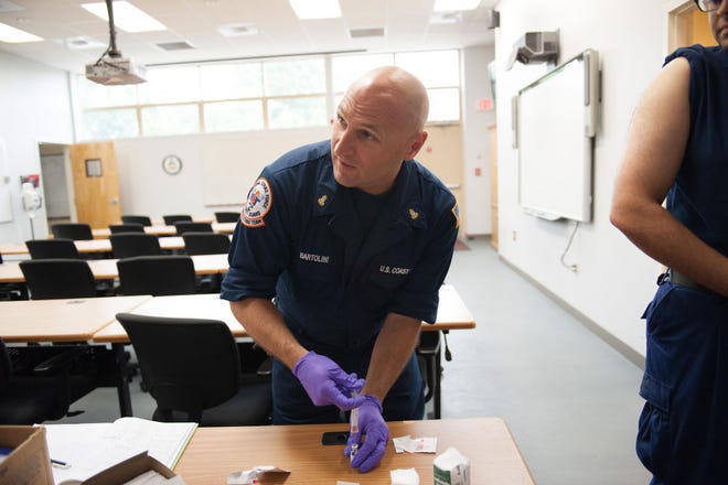 Chief Petty Officer David Bartolini, a member of the Coast Guard's Atlantic Strike Team, prepares to give a vaccination to one of his men at Joint Base McGuire-Dix-Lakehurst.