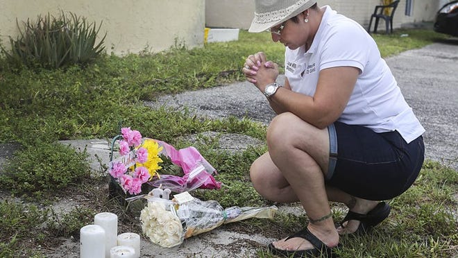 After placing flowers in front of the Greenacres home where police say 53 year-old Nilda Sheffield killed her daughter and two grandchildren, Greenacres councilwoman Lisa Rivera kneels in a moment of silence Sunday, June 28, 2015. Rivera said, "So close to home you never think it's gonna happen. I just wanted to come and bring my condolences."v (Damon Higgins / The Palm Beach Post)