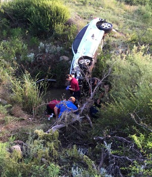 In this photo provided by Brandon Cogburn, workers stand near the wrecked car of Wanda Mobley where she was found Sunday, June 28, 2015, near Seymour, Texas. The 75-year-old woman says she couldn't walk after crashing her car into a ravine in North Texas, but survived for two days after pulling herself through a broken windshield and soaking her T-shirt in a nearby pond to get water. (Brandon Cogburn via AP)