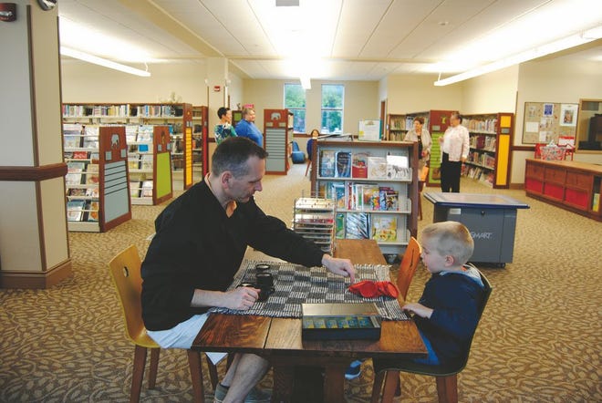 Nick Padgett of Macomb plays a game of checkers with his son Theo, 3, in the Macomb Public Library’s children’s section. An open house was held Sunday to show off an expansion that added 10,000 square feet to the Carnegie library. The library’s board of trustees pursued the expansion after the library began to outgrow its space in the building, which was constructed in 1904.