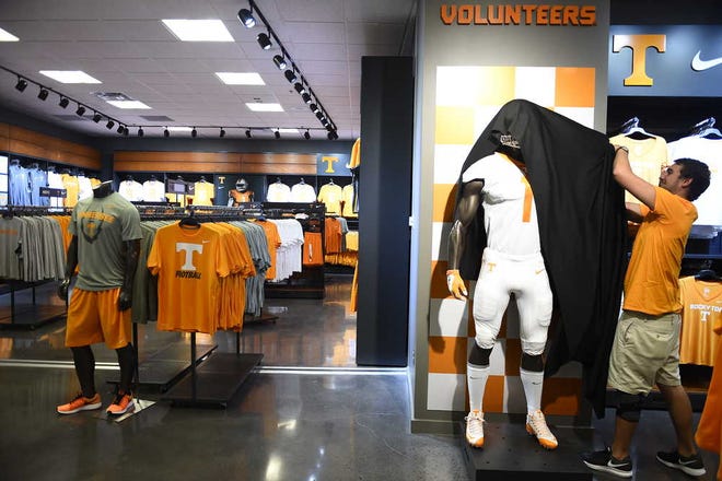 Vol Shop employee Thomas Shelton removes a cover from a mannequin with the new Nike football uniform inside Neyland Stadium on Wednesday. Nike took over as Tennessee's main apparel provider as part of an eight-year contract worth about $35 million. (Amy Smotherman Burgess/Knoxville News Sentinel via AP)