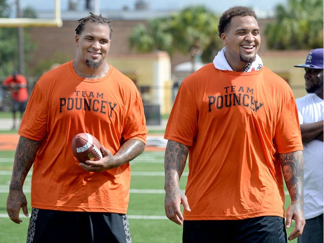 Mike (left) and Maurkice Pouncey have fun watching the kids do drills at the 5th Annual Pouncey Football and Cheer Camp at Bryant Stadium in Lakeland on Saturday June 27, 2015. About 700 kids participated in three-hour long camp.