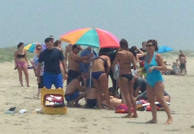 People surround and attend to a 68-year-old man that was bit by a shark in waist-deep water off Ocracoke Island, N.C., Wednesday, July 1, 2015. The man suffered wounds to his ribcage, lower leg, hip and both hands as he tried to fight off the shark. (Laura I. Hefty via AP)