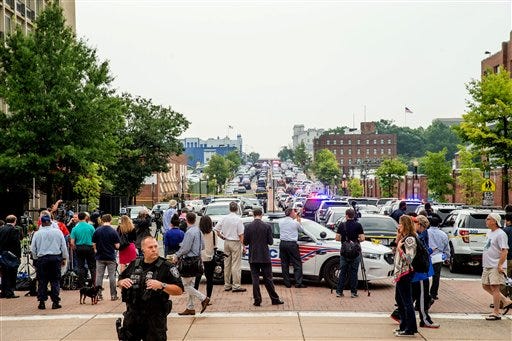 Members of the media and pedestrians gather along M Street in Southeast Washington today. The Washington Navy Yard was on lockdown this morning after reports of gunshots, but a senior federal law enforcement official says there has been no confirmed report of any shooting. (AP Photo / Andrew Harnik)