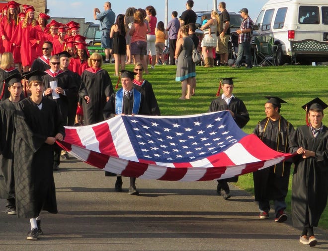 Seven members of the Port Jervis High School Class of 2015 have enlisted in the military. They led their class from the high school and onto Chase field with this gigantic unfurled American flag. From left: Aaron Cody Hnida (Marine Corps), Gary C. Lanterman (Navy), Alex Edward Quick (Air Force), Jordan M. Presto (Air National Guard), Anthony Vito Spagnola (Navy), Jordan Colin Lopez (Army), and Troy Evan Chuckran (Air Force). Sharon Siegel/For the Gazette