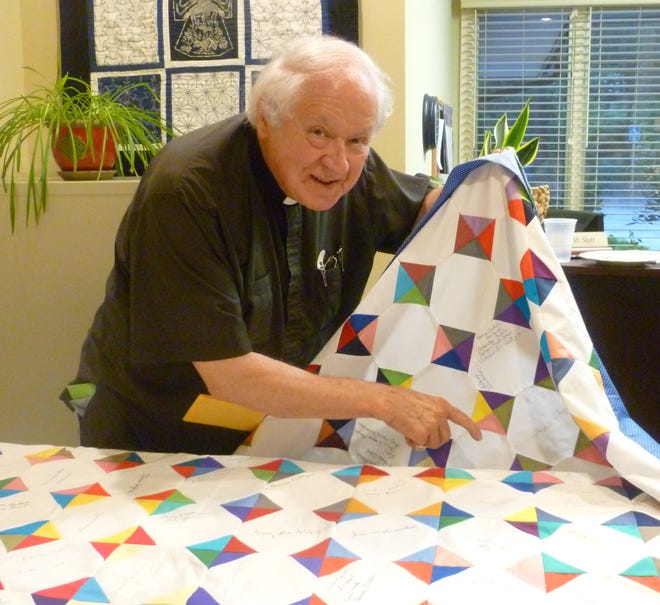 Father Alex Viola admires the quilt presented to him at the conclusion of the Festive Eucharist. The quilt was made in 17 days by the women of St. John in the Wilderness. More than 225 blocks were completed. The blocks were sewn together by parish member Worth Gordon. Cash donations made toward the quilt will be used to finish the back of the quilt.