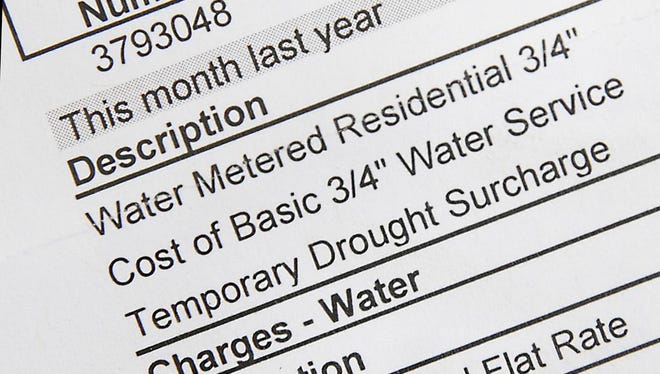 In this photo taken June 23, 2015, Cat Kaslan displays one of her monthly water bills that shows the temporary drought surcharge for her home in Roseville, Calif. Kaslan has replaced the lawn in her front yard with drought resistant plants and says the surcharge has been fairly negligible, although she expected to see her conservation efforts result in greater savings. Californians who thought their water bills would be reduced as they conserve water have found local water agencies are charging more for water and charging "drought surcharges" to make up lost revenue. (AP Photo/Rich Pedroncelli)