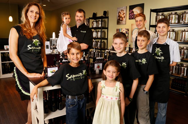 Katrine and Keith Dunn pose with their children, from left, Julia, 3; Oliver, 8; Liberty, 5; Simon, 11; Wyatt, 10; Ian Hazzard, 16; and Jesse, 13; at their specialty oil, balsamic vinegar and spice shop, Saporito.