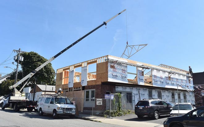 In this file photo, a roof truss is lifted by crane to the top of Mesa 21, as the fire-ravaged restaurant is rebuilt.