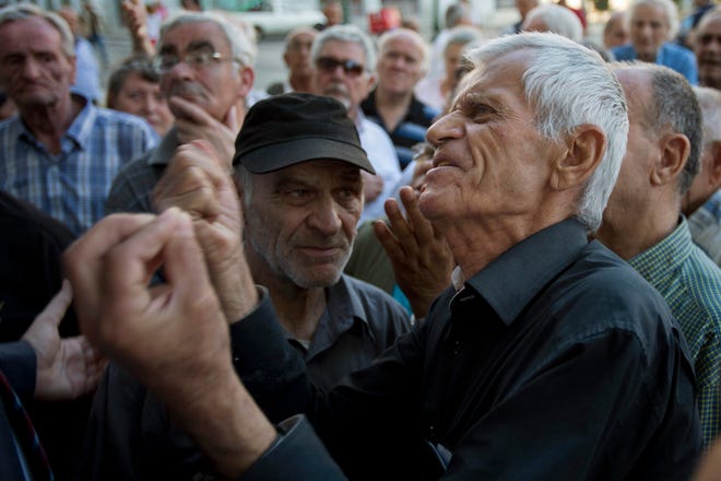 Elderly people argue with a bank worker as they wait to be allowed into the bank to withdraw a maximum of 120 euros ($134) for the week in Athens, Monday, July 6, 2015. (AP Photo/Emilio Morenatti)