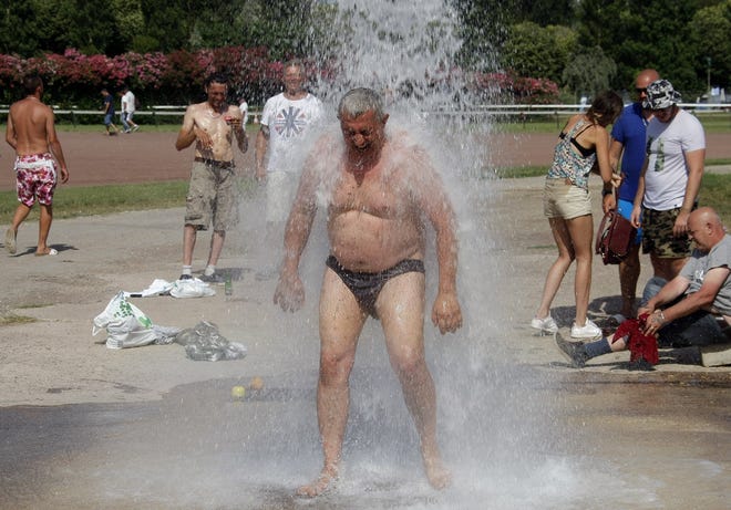 A man cools off under big shower, in Marseille, southern France, Sunday July 5, 2015. A mass of hot air moving north from Africa is bringing unusually hot weather to Western Europe, with France in recent days experiencing temperatures around 34 degrees Celsius (93 Fahrenheit).