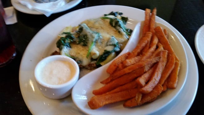 Monterey chicken, cloaked in spinach, artichokes and Monterey jack cheese, is served with sweet potato fries. News-Journal/Edward Lawson