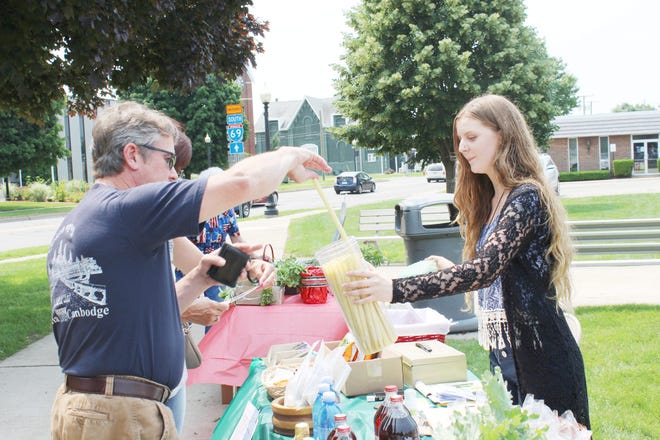 A shopper reaches for a beeswax cone sold from the Pure Earth table during Saturday's market. Spencer Lahr Photo