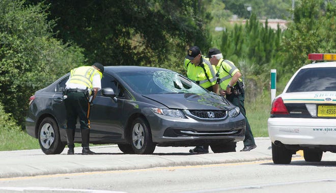 A St. Johns County Sheriff's deputy and public service assistants look in to a car involved in an accident where a man was hit on U.S. 1 North on Wednesday, July 8, 2015. The man was taken to Flagler Hospital where he died according to the St. Johns County Sheriff's Office. The wreck happened near Lewis Speedway in St. Augustine about 8:45 a.m.