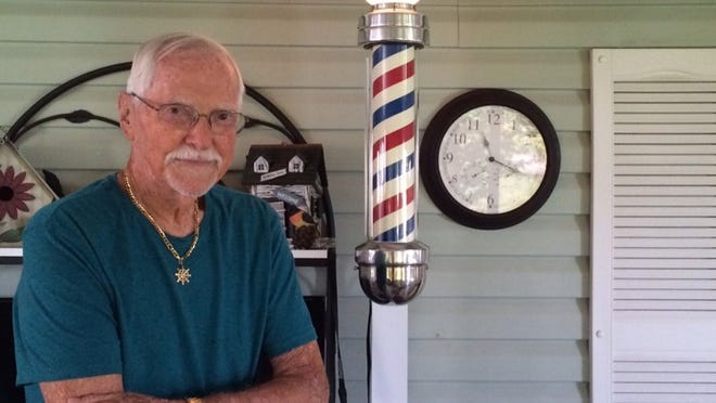 Dell Savage poses at his home with the barber pole that used to be at his Twin City Barber Shop in North Palm Beach. The shop is closing July 18, but Savage isn’t giving up barbering. (The Palm Beach Post/Sarah Peters)
