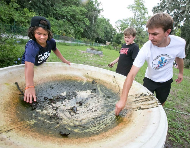 Evan Abbott, 12, left, Andrew Mauney, 10, center and Ricky Regnier, right, adult leader, work on cleaning a huge bird bath Friday afternoon.