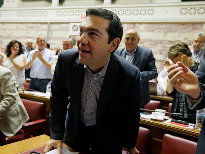 Greece's Prime Minister Alexis Tsipras arrives for a meeting as his lawmakers of Syriza party applaud him at the Greek Parliament in Athens on Friday.