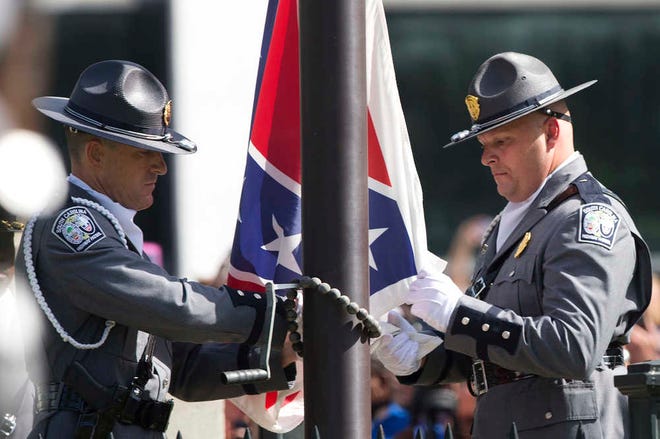 An honor guard from the South Carolina Highway patrol lowers the Confederate battle flag as it is removed from the Capitol grounds Friday, July 10, 2015, in Columbia, S.C. The Confederate flag was lowered from the grounds of the South Carolina Statehouse to the cheers of thousands on Friday, ending its 54-year presence there and marking a stunning political reversal in a state where many thought the rebel banner would fly indefinitely. (AP Photo/John Bazemore)