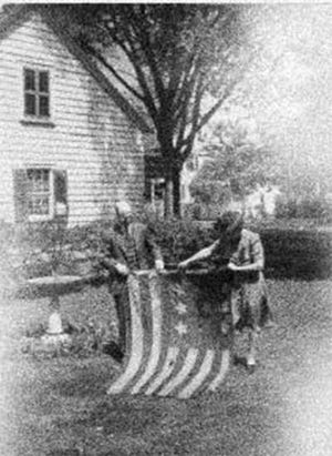 Gertrude Carraway of the New Bern Historical Society and an unidentified man unfurl a Civil War Confederate flag in 1940 after it was returned to New Bern by a historical group in Massachusetts.