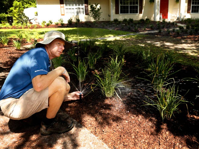 Kevin Brasington, owner of Aqua Turf Irrigation, adjusts a newly installed irrigation system for customer Mike Wierzbowski in northwest Gainesville Thursday, July 9, 2015. The sprinkler heads are MP Rotators, manufactured by Hunter Industries, which claim to reduce water use by 30 percent.