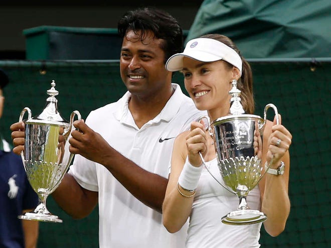 Leander Paes of India, left, and Martina Hingis of Switzerland hold up the trophies after winning the mixed doubles final against Alexander Peya of Austria and Timea Babos of Hungary at the All England Lawn Tennis Championships in Wimbledon, London, Sunday July 12, 2015. (AP Photo/Alastair Grant)