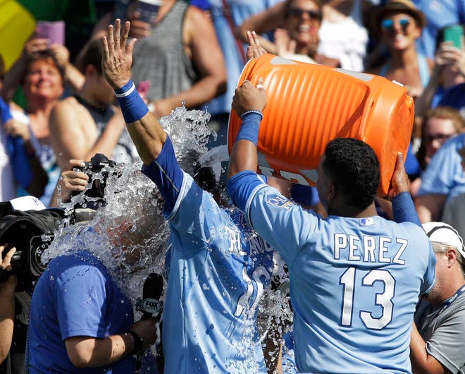 Kansas City Royals catcher Salvador Perez, right, dumps water on teammate Paulo Orlando, middle, and FSKC announcer Joel Goldberg following Sunday's game against the Toronto Blue Jays at Kauffman Stadium in Kansas City, Mo. Orlando hit a tiebreaking home run in the bottom of the eighth inning and the Royals won 11-10.