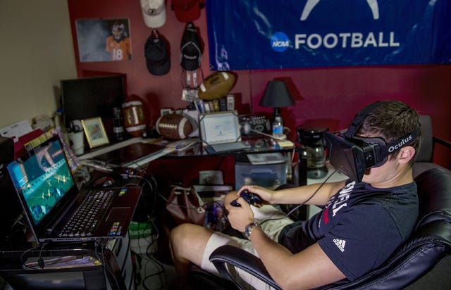Nick West, a quarterback at William Jewell College, demonstrates running plays while wearing a virtual reality headset on June 22, 2015, at the Mabee Center on William Jewell's campus in Liberty, Mo. (Allison Long/Kansas City Star/TNS) 
 Brendan Reilly, CEO of Eon Sports, poses for a portrait on June 17, 2015 in Kansas City, Mo. Eon Sports developed Sidekiq, virtual reality software for training football players. (Allison Long/Kansas City Star/TNS) 
 Eon Sports makes Sidekiq, a mobile phone application that works with a virtual reality headset like the one pictured to help train football players. (Allison Long/Kansas City Star/TNS) 
 Brendan Reilly, CEO of Eon Sports, wears a virtual reality headset playing the company's Sidekiq software, which is used for training football players, on June 17, 2015, in Kansas City, Mo. (Allison Long/Kansas City Star/TNS)