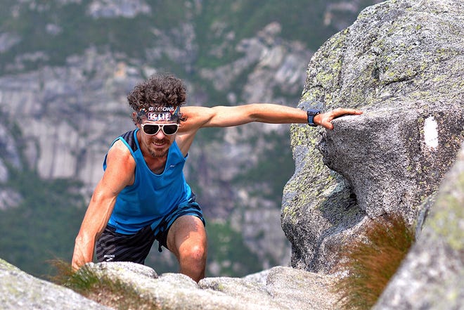 In this Sunday, July 12, 2015 photo released by the Brooks Running Company, Scott Jurek, of Boulder, Colo., climbs to the summit of Mount Katahdin near Millinocket, Maine, before completing the Appalachian Trail in what he claims is record time. Jurek, winner of several ultramarathon races, began at Springer Mountain in northern Georgia on May 27. (Luis Escobar/Brooks Running Company via AP)