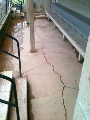 Standing water and cracks are visible in the dugout along the first base line at Washington Community High School's Brian Wisher Field.